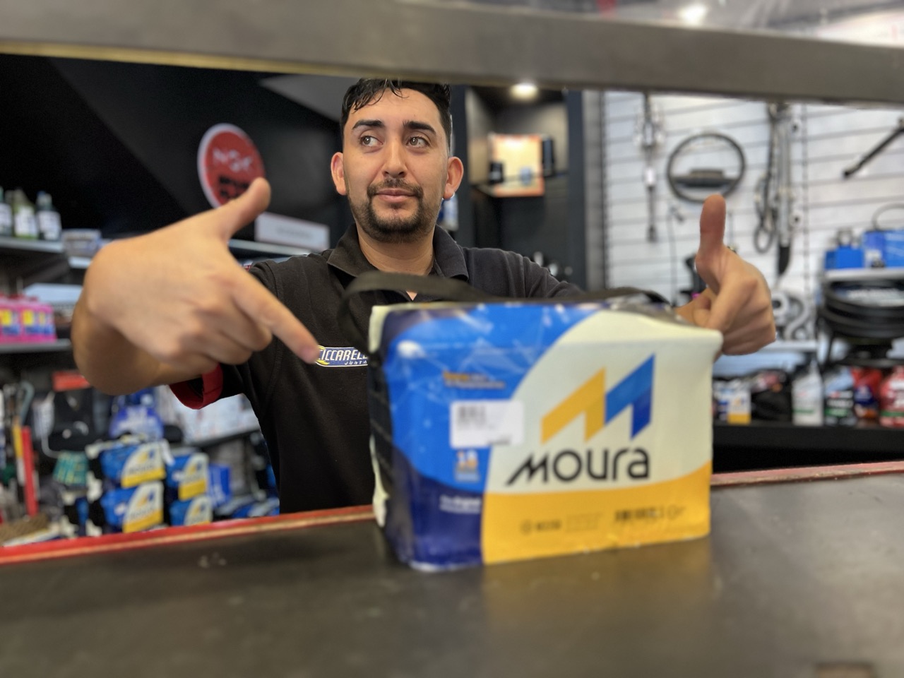 Vendedor de MM Repuestos mostrando una batería Moura, representantes oficiales en Mendoza